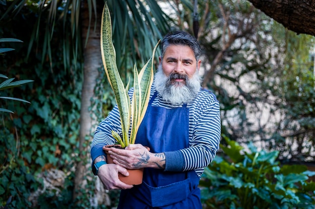 Hombre barbudo cuidando sus plantas en el jardín de casa