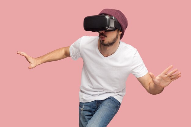 Hombre barbudo emocionado con las manos extendidas usando vr jugando videojuegos tratando de encontrar la salida en la búsqueda