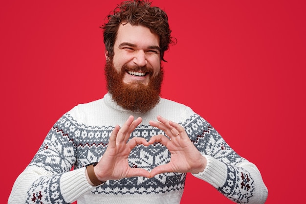 Hombre barbudo emocionado sonriendo y mostrando gesto de corazón