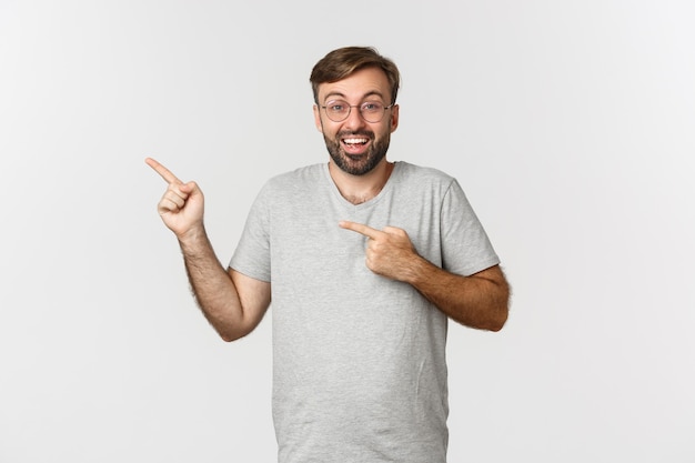 Hombre barbudo emocionado sonriendo, señalando con el dedo en la esquina superior izquierda