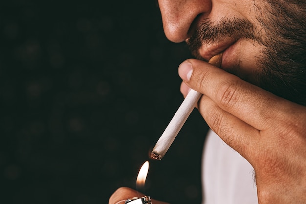 Foto hombre barbudo encendiendo cigarrillos con encendedor de fuego