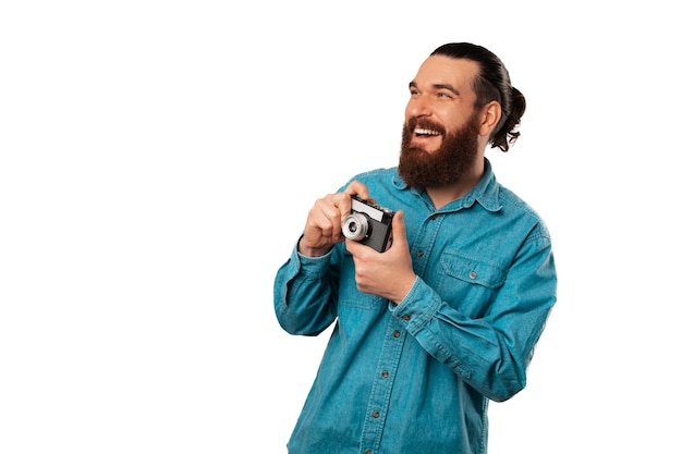 Foto hombre barbudo extasiado con camisa azul sostiene una vieja cámara vintage