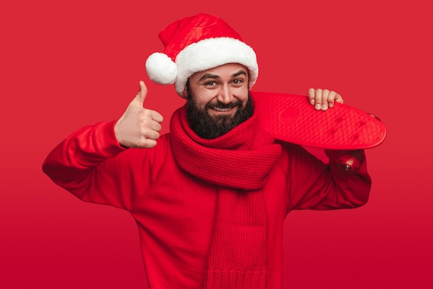 Hombre barbudo feliz en bufanda tejida y gorro de Papá Noel