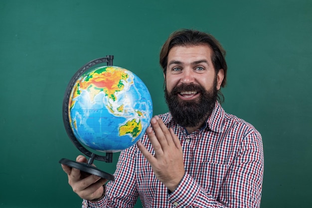 Hombre barbudo feliz en camisa a cuadros mirando la educación escolar de geografía del mundo geográfico