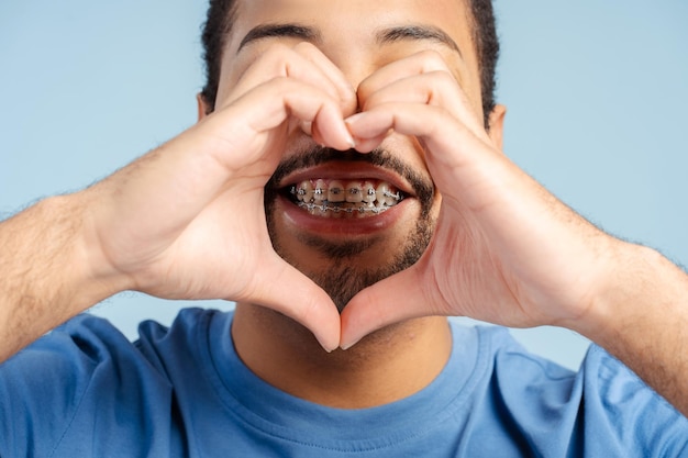 Hombre barbudo feliz haciendo un gesto de señal de corazón con las manos cerca de los labios