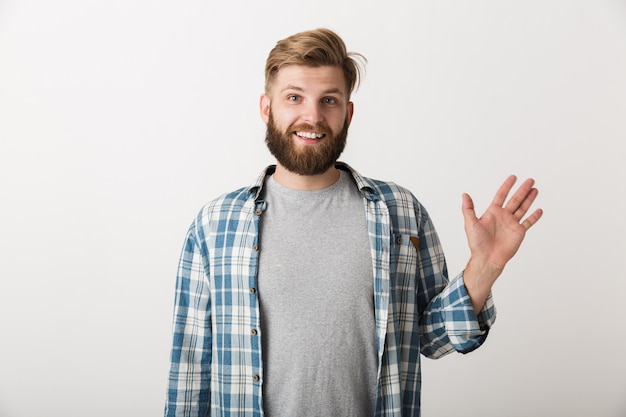 Hombre barbudo feliz vestido con camisa a cuadros que se encuentran aisladas, agitando la mano