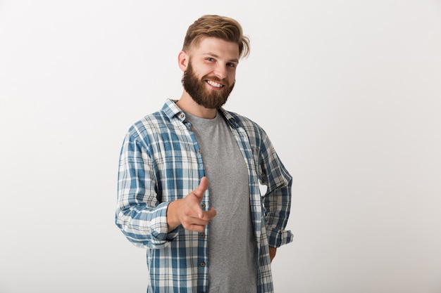 Hombre barbudo feliz vestido con camisa a cuadros que se encuentran aisladas, apuntando a la cámara