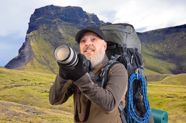 hombre barbudo fotógrafo turístico con una mochila fotografías la belleza de la naturaleza en las montañas