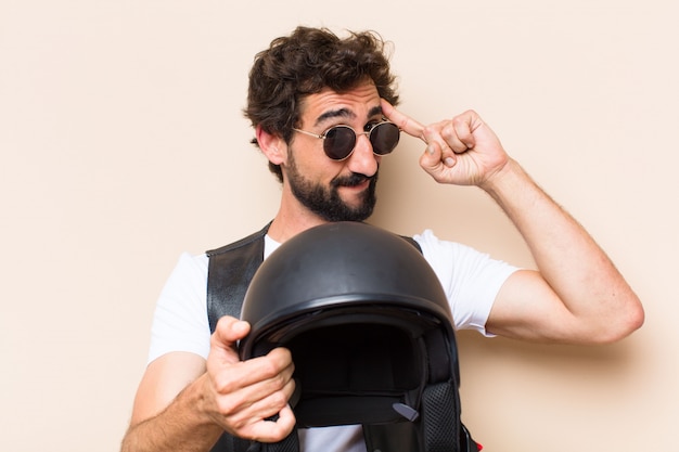 Hombre barbudo fresco joven con un casco pensando