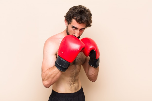 Hombre barbudo fresco joven con guantes de boxeo y lucha contra el concepto de fitness