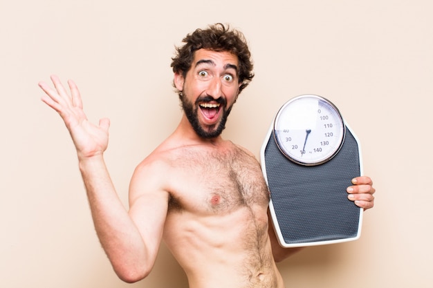 Hombre barbudo fresco joven sosteniendo un concepto de fitness de equilibrio o escala