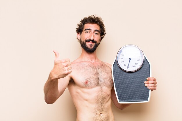 Hombre barbudo fresco joven sosteniendo un concepto de fitness de equilibrio o escala