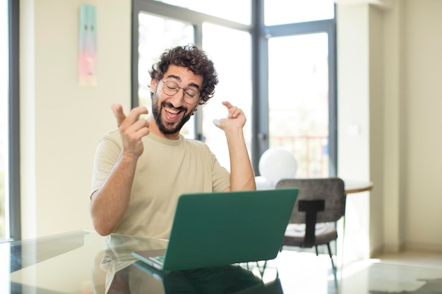 Foto hombre barbudo fresco que trabaja en casa en una computadora portátil