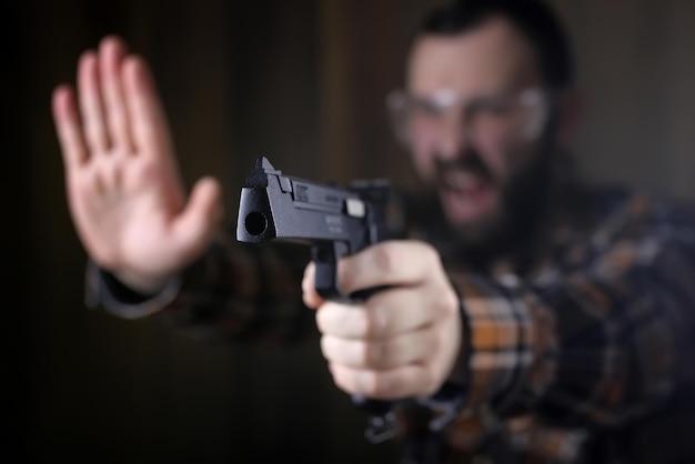 Hombre barbudo con gafas protectoras y entrenamiento auditivo en tiro con pistola