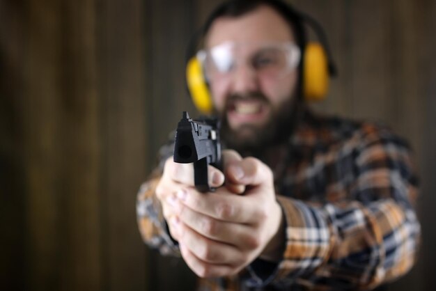 Hombre barbudo con gafas protectoras y entrenamiento auditivo en tiro con pistola