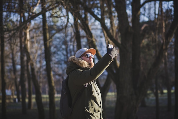 Un hombre barbudo con gafas de sol y una chaqueta se toma un selfie