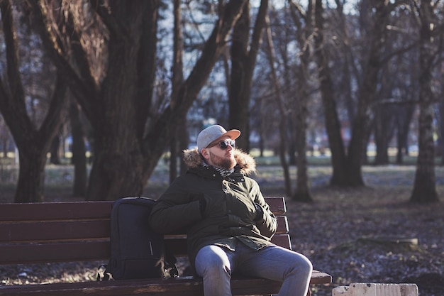 Hombre barbudo con gafas de sol descansando después de un paseo por el parque