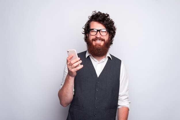 Hombre barbudo con gafas sosteniendo un teléfono