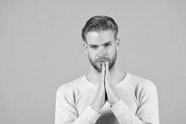 Hombre barbudo con gesto de manos rezando Hombre con barba en la cara sin afeitar y cabello rubio Modelo de moda en camiseta casual Meditación o concepto zen y paz