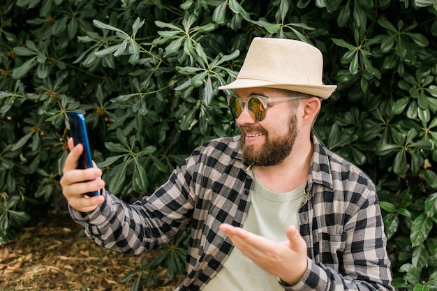 Hombre barbudo haciendo videollamadas en el concepto de tecnología y conexión de video al aire libre del teléfono inteligente