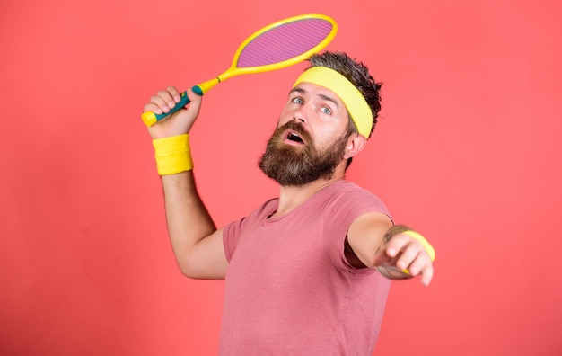 Hombre barbudo hipster usar ropa deportiva Jugador de tenis moda retro Tenis deporte y entretenimiento Atleta hipster sostener raqueta de tenis en mano fondo rojo Jugar tenis por diversión Alcanzar la cima de nuevo