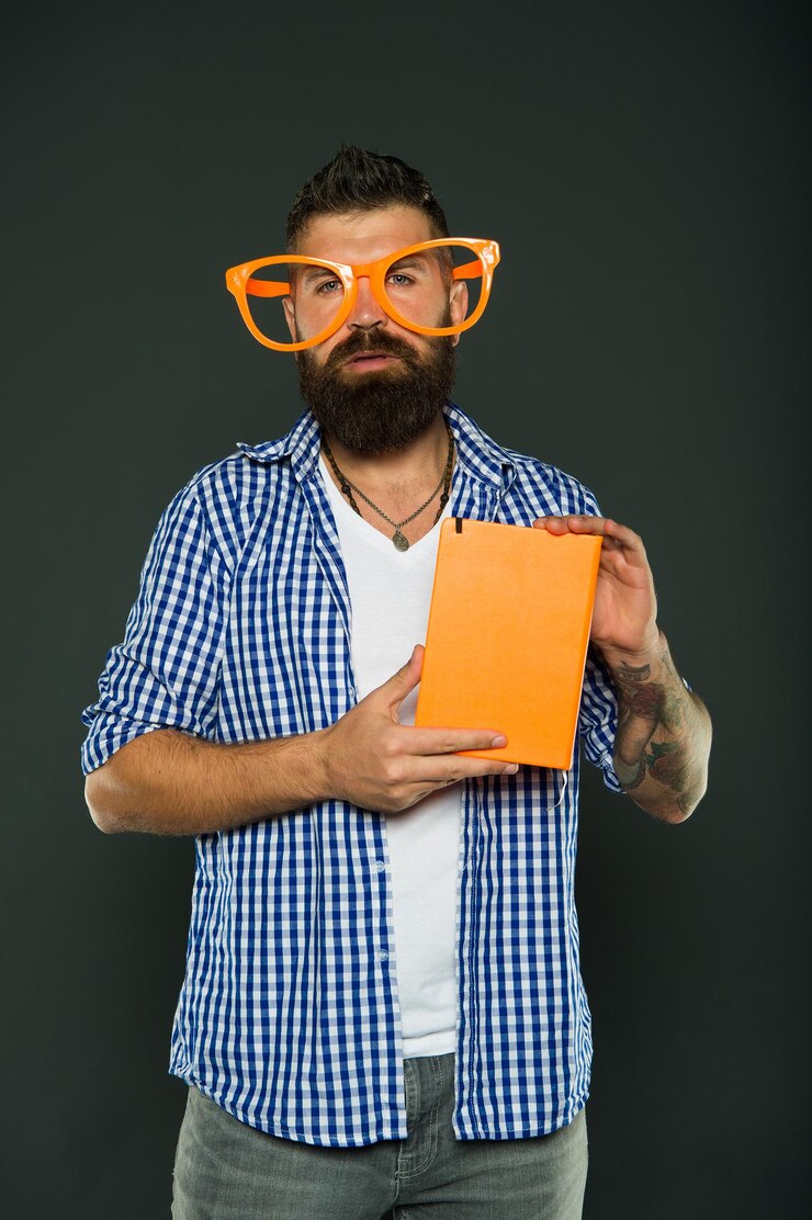 Foto hombre barbudo inconformista use anteojos divertidos sostenga bloc de notas o libro. ilumina tu día. lee este libro. sentido cómico y humorístico. historia divertida. estudiar es divertido. libro divertido para relajarse. espacio de copia de portada de libro.