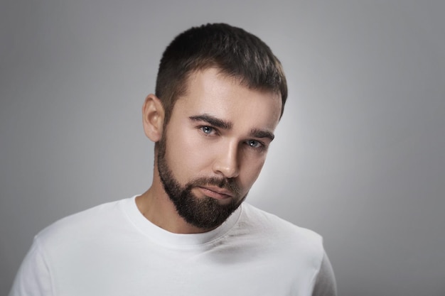 Hombre barbudo joven y guapo con piel limpia sobre fondo gris