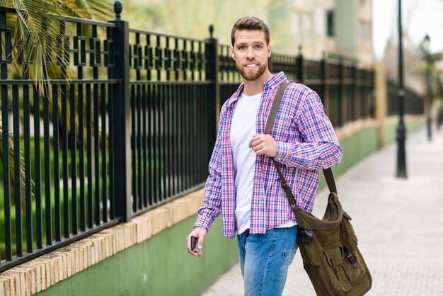 Hombre barbudo joven que camina en fondo urbano. Concepto de estilo de vida