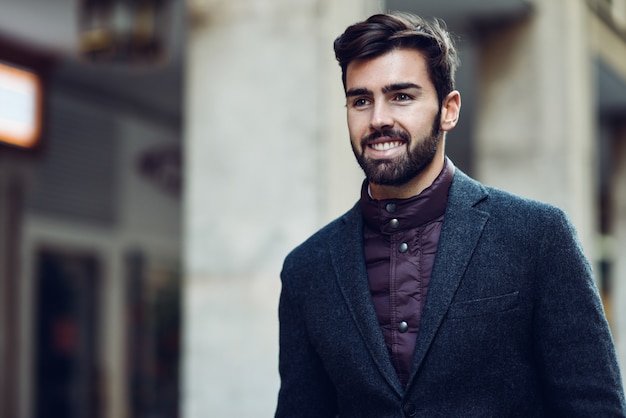 Hombre barbudo joven que lleva el traje elegante británico en la calle.