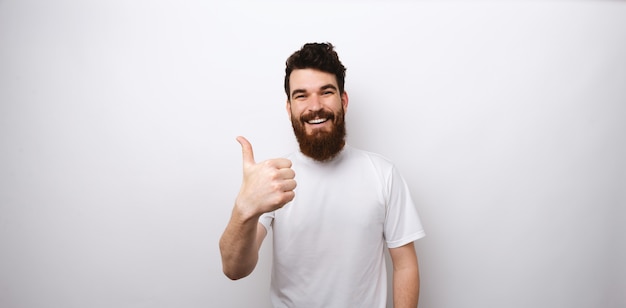 Foto hombre barbudo joven que muestra como gesto con el pulgar para arriba.