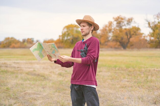 Hombre barbudo joven en sombrero de verano perdido en el bosque y buscar el camino en el mapa