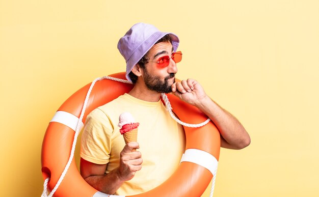 Hombre barbudo loco expresivo con sombrero y gafas de sol con un helado