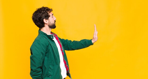 Hombre barbudo loco joven contra el espacio de copia de pared naranja.