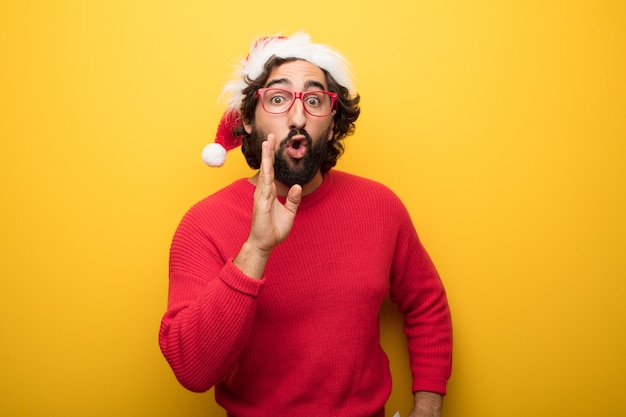 Hombre barbudo loco joven que lleva los vidrios rojos y el sombrero de Papá Noel