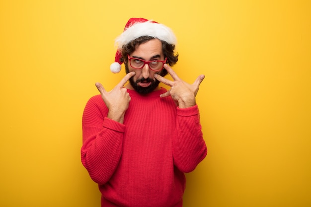 Hombre barbudo loco joven que lleva los vidrios rojos y el sombrero de Papá Noel