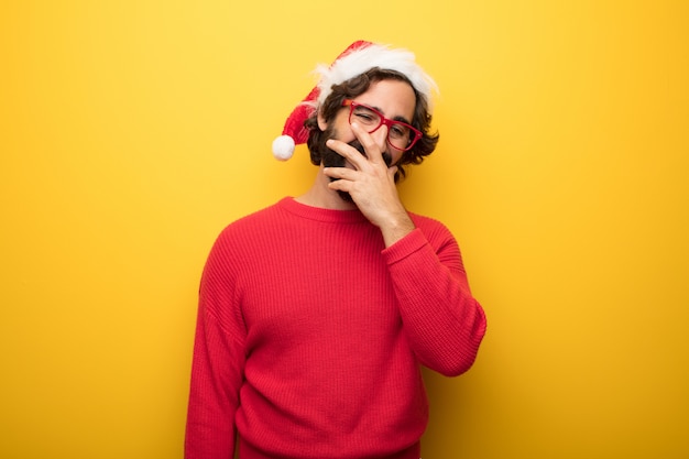 Hombre barbudo loco joven que lleva los vidrios rojos y el sombrero de Papá Noel