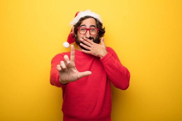 Hombre barbudo loco joven que lleva los vidrios rojos y el sombrero de Papá Noel