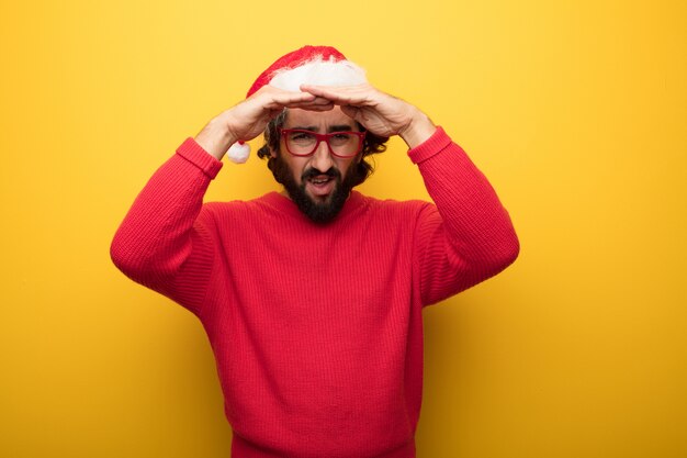 Hombre barbudo loco joven que lleva los vidrios rojos y el sombrero de Papá Noel