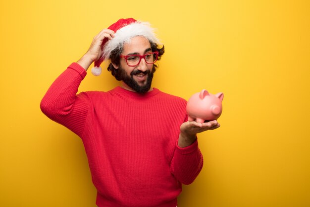 Hombre barbudo loco joven que lleva los vidrios rojos y el sombrero de Papá Noel