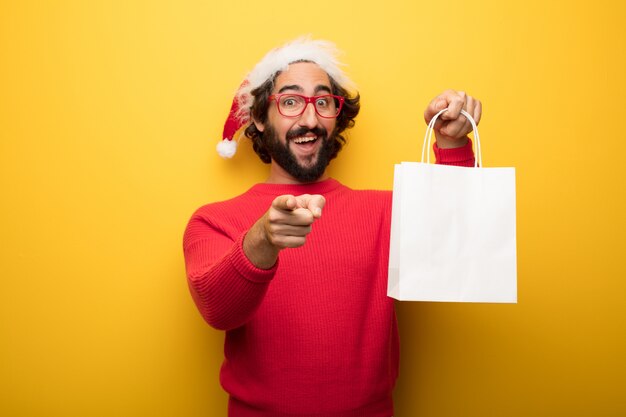 Hombre barbudo loco joven que lleva los vidrios rojos y el sombrero de Papá Noel