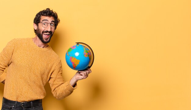Hombre barbudo loco joven que sostiene un mapa del globo del mundo.