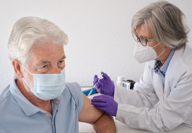 Hombre barbudo con mascarilla quirúrgica vacunado, covid-19 de una doctora. Concepto de vacunación por coronavirus