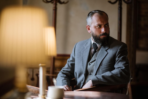 Hombre barbudo de mediana edad con traje retro sentado en el restaurante