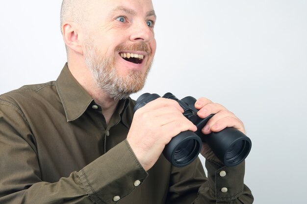 Hombre barbudo mirando a través de binoculares en la distancia