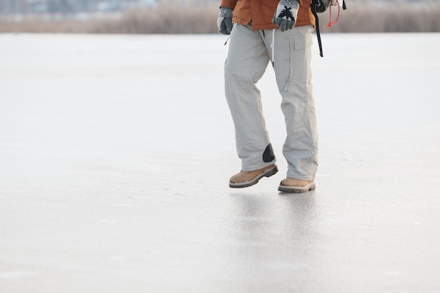 Un hombre barbudo con una mochila con ropa cálida de invierno camina sobre un lago congelado en invierno El concepto de senderismo y estilo de vida activo