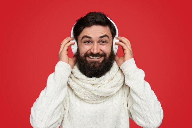 Hombre barbudo de moda en bufanda escuchando música