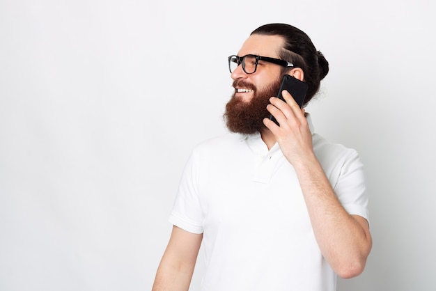 El hombre barbudo moderno está hablando por teléfono y mirando a un lado.