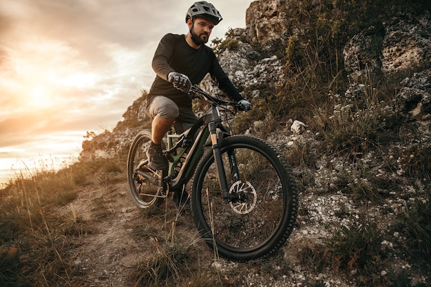 Hombre barbudo montando bicicleta en las montañas