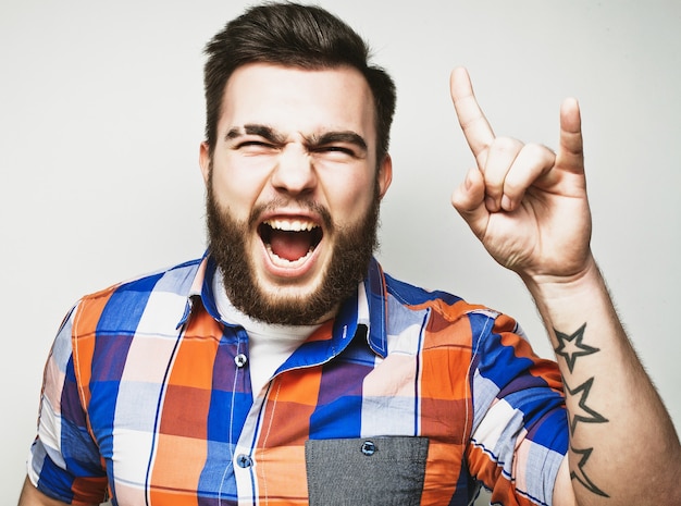 Hombre barbudo mostrando gesto pesado sobre fondo gris