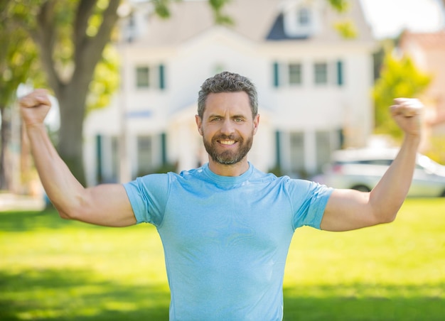 Hombre barbudo musculoso feliz de pie celebrando la compra del propietario de la casa